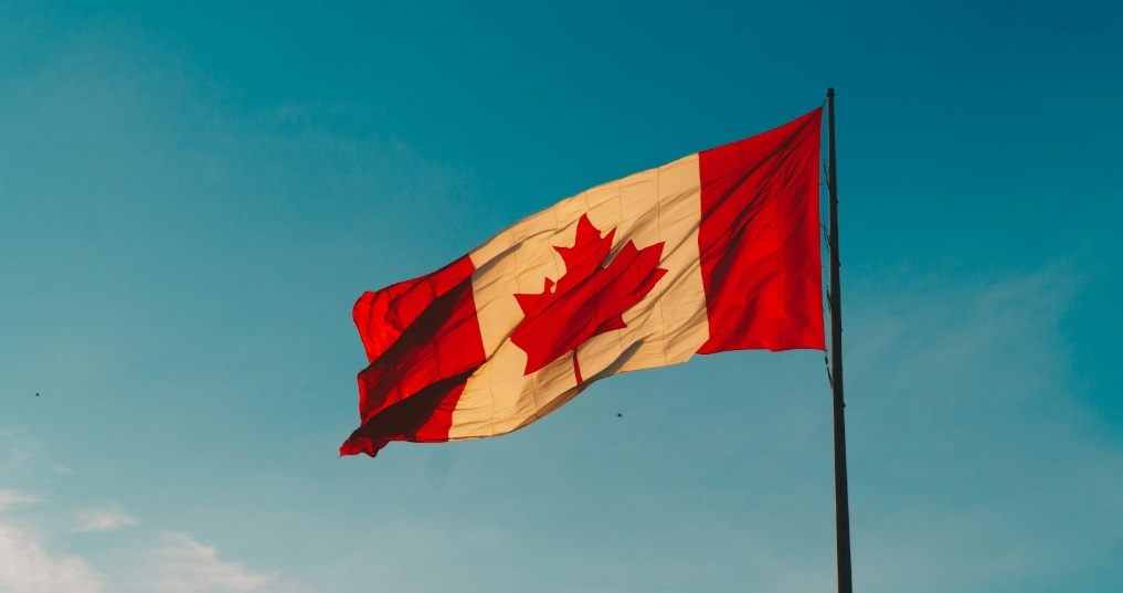 Canadian flag waving against a clear, blue sky